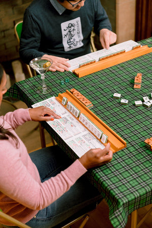 Reading the mahjong card mid-game at a green cloth table