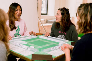 Friends laughing over a game of American Mahjong