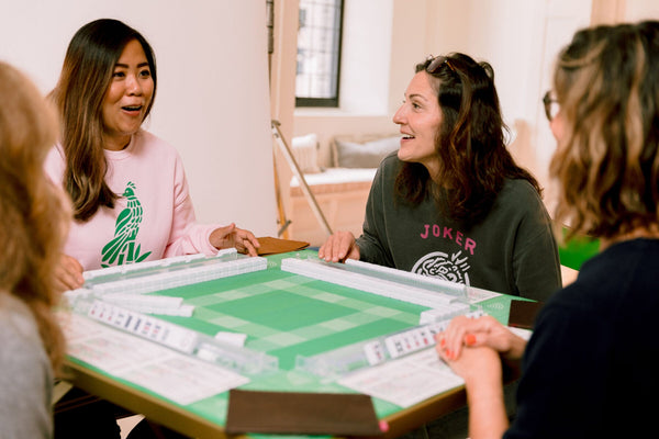 Friends laughing over a game of American Mahjong