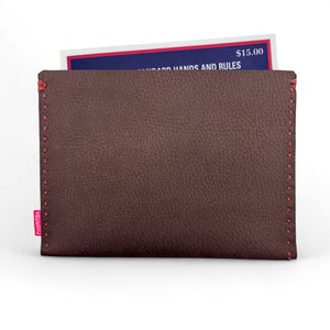 Brown leather cardholder with red stitching holding a card on a white background